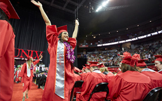 A line of African-American graduates in red robes walk down the aisle during a commencement ceremony.