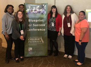FY_BlueprintForSuccessConf1_10-27-19 Laura Obrist poses for a photo with other conference attendees before a banner that reads 'Blueprint for Success Conference'