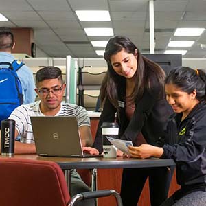 A trio of students gather around a laptop.