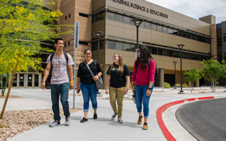 Four students walk along a sidewalk at the NSC campus