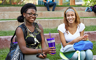 Two African-American students smile for the camera as they sit on the steps of the outdoor amphitheater on the UNLV Quad.