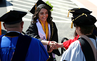 A smiling graduate faces three people who's backs are to the viewer.