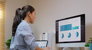 A professional works at their computer using a standing desk