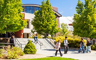 Image of Truckee Meadows Community College campus with bright green trees and students walking.