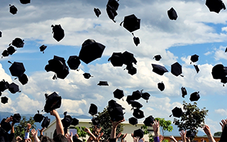 Group of graduates throwing caps into the air.