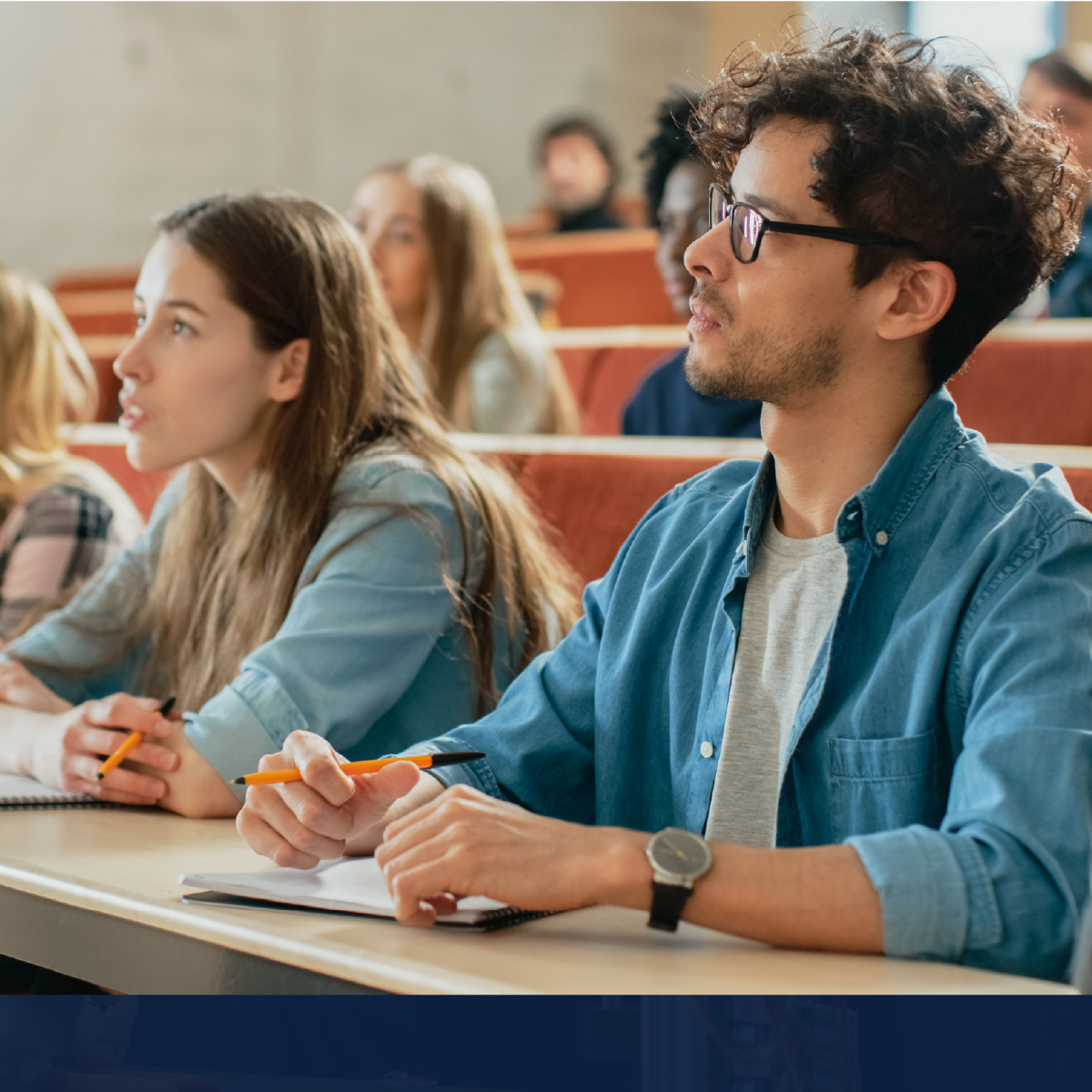 Two students sit in a lecture hall in rapt attention