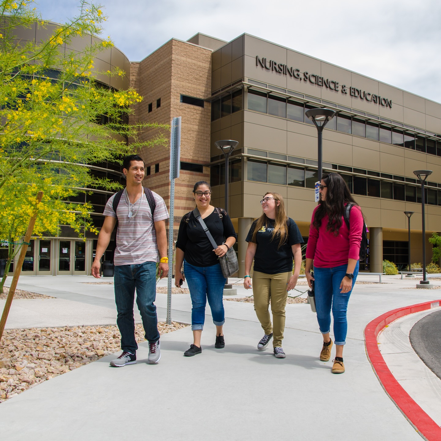A student wearing a t-shirt that reads "Educating Nevada" listens intently to a lecturer a few feet away
