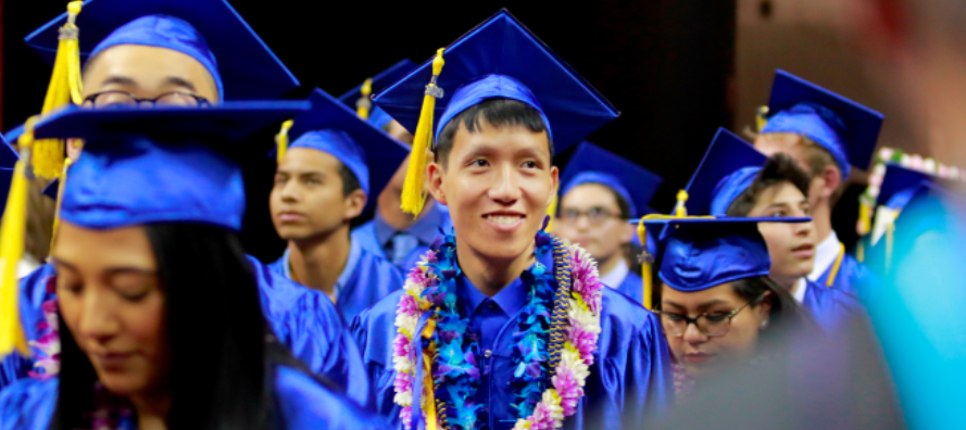 An audience of CSN graduates in blue caps and gowns
