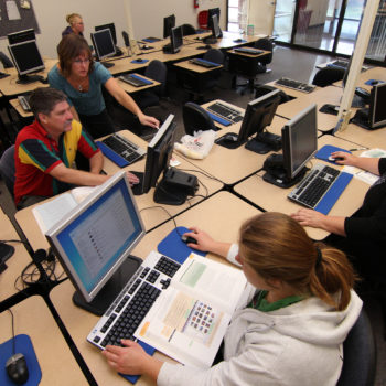 An instructor works with students in a computer class at WNC